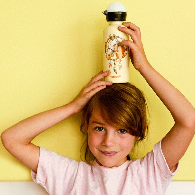 SIGG lasten malliston pääkuvassa tytöllä ihana SIGG lasten pullo päänsä päällä.